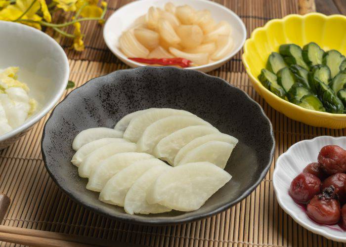 Bowls filled with different types of pickles, including cucumbers, onions and radish.